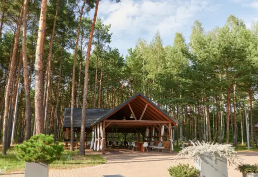 Wokół wiaty znajduje się dużo zieleni, co zapewnia przyjemny klimat i prywatność. Miejsce to jest doskonałą opcją dla tych, którzy cenią sobie bliskość natury, relaks i smaczne jedzenie na świeżym powietrzu.